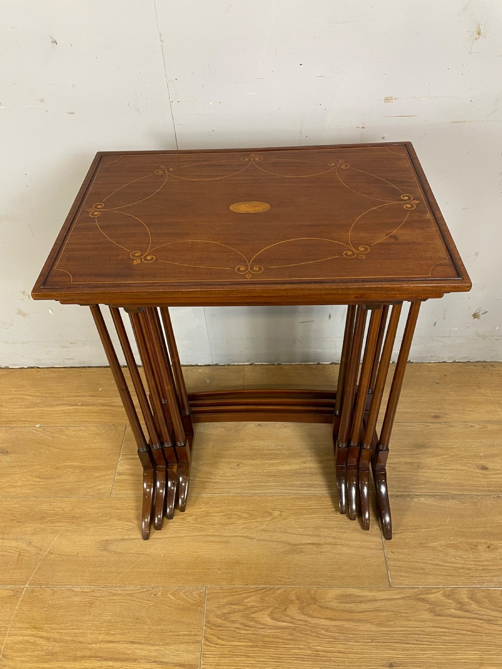 An Edwardian nest of four rectangular mahogany tables featuring satinwood floral line inlay and slender turned legs resting on trestle feet. View XI
