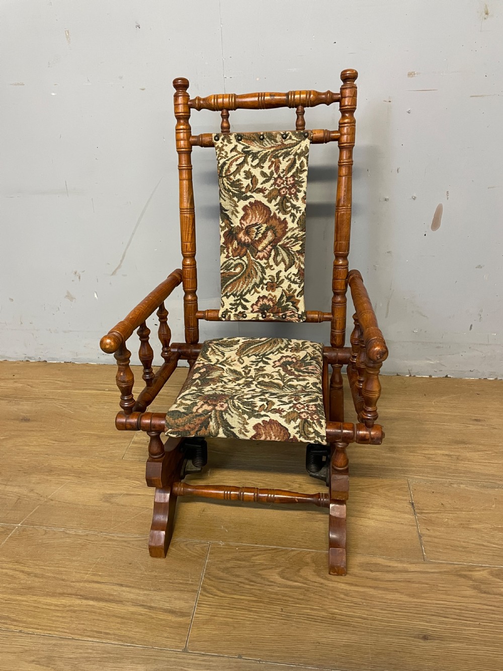 A 19th-century childs American platform rocking chair made of turned wood with floral tapestry fabric on the seat and backrest. View II