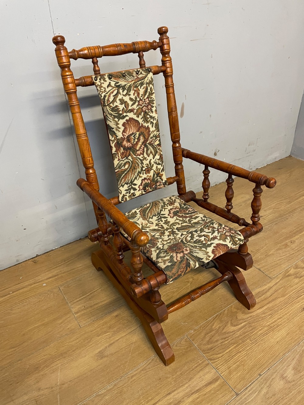 A 19th-century childs American platform rocking chair made of turned wood with floral tapestry fabric on the seat and backrest. View III