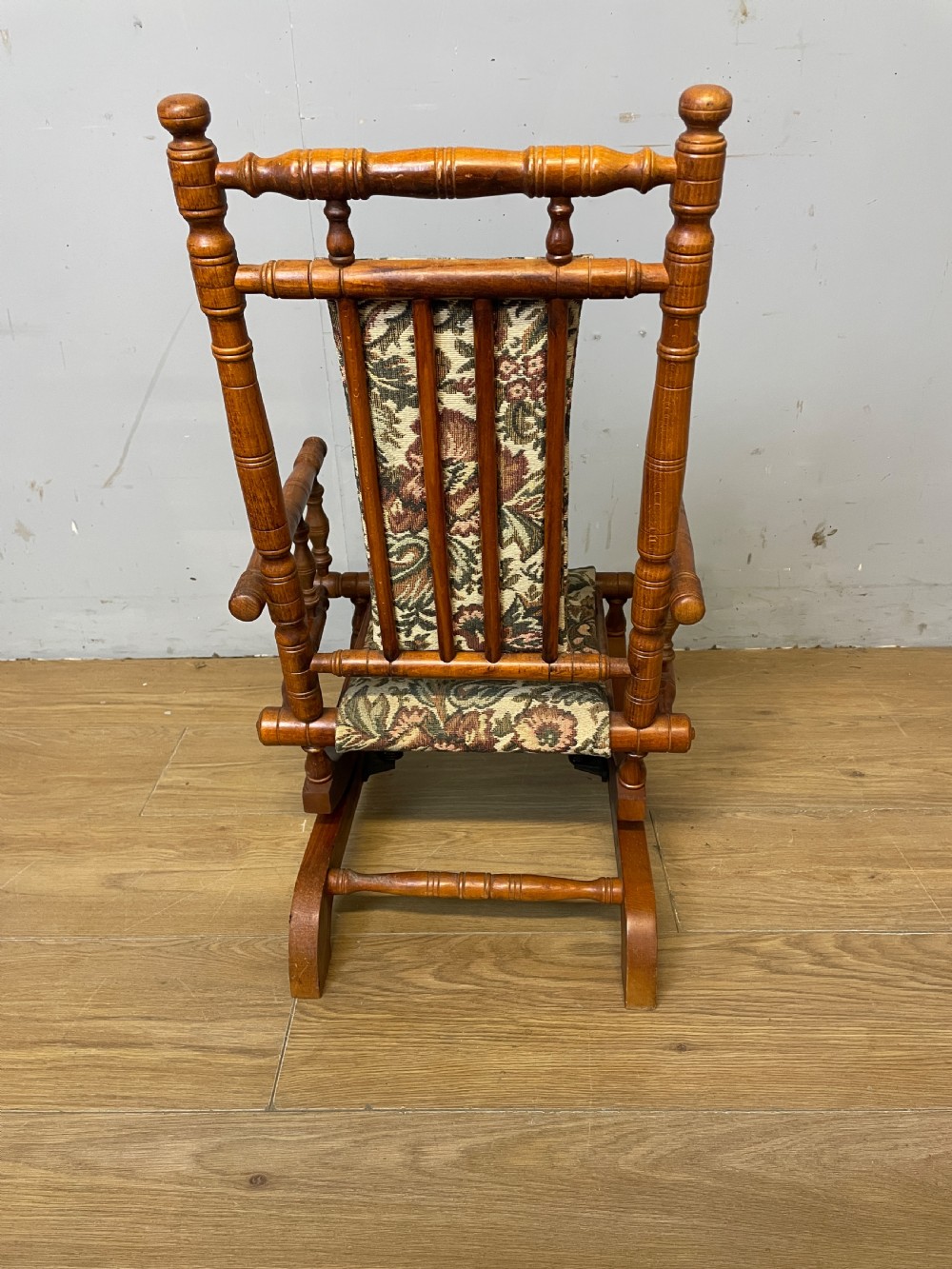 A 19th-century childs American platform rocking chair made of turned wood with floral tapestry fabric on the seat and backrest. View V