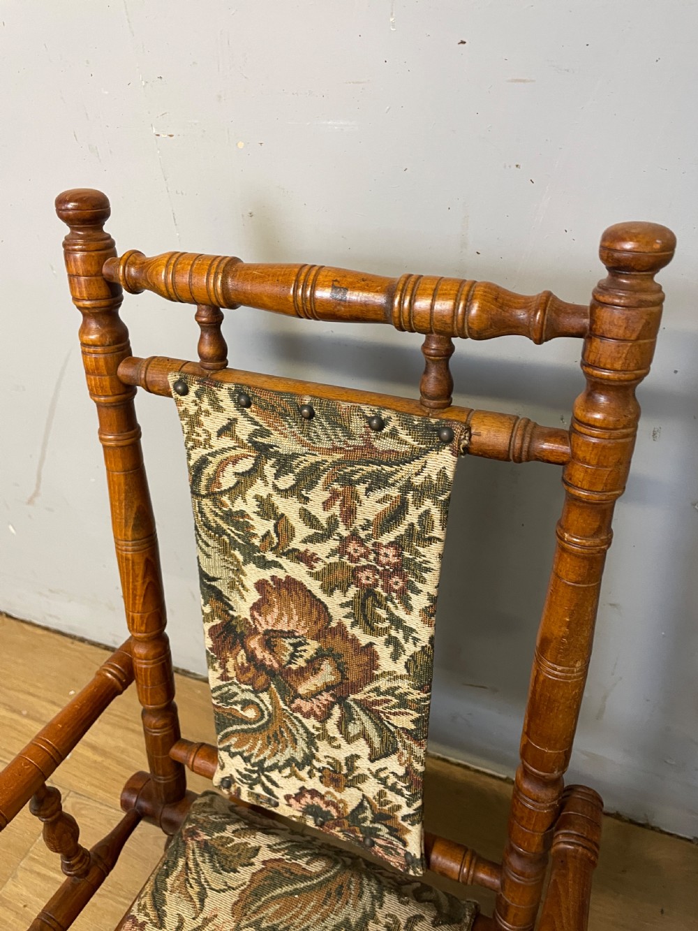 A 19th-century childs American platform rocking chair made of turned wood with floral tapestry fabric on the seat and backrest. View VI