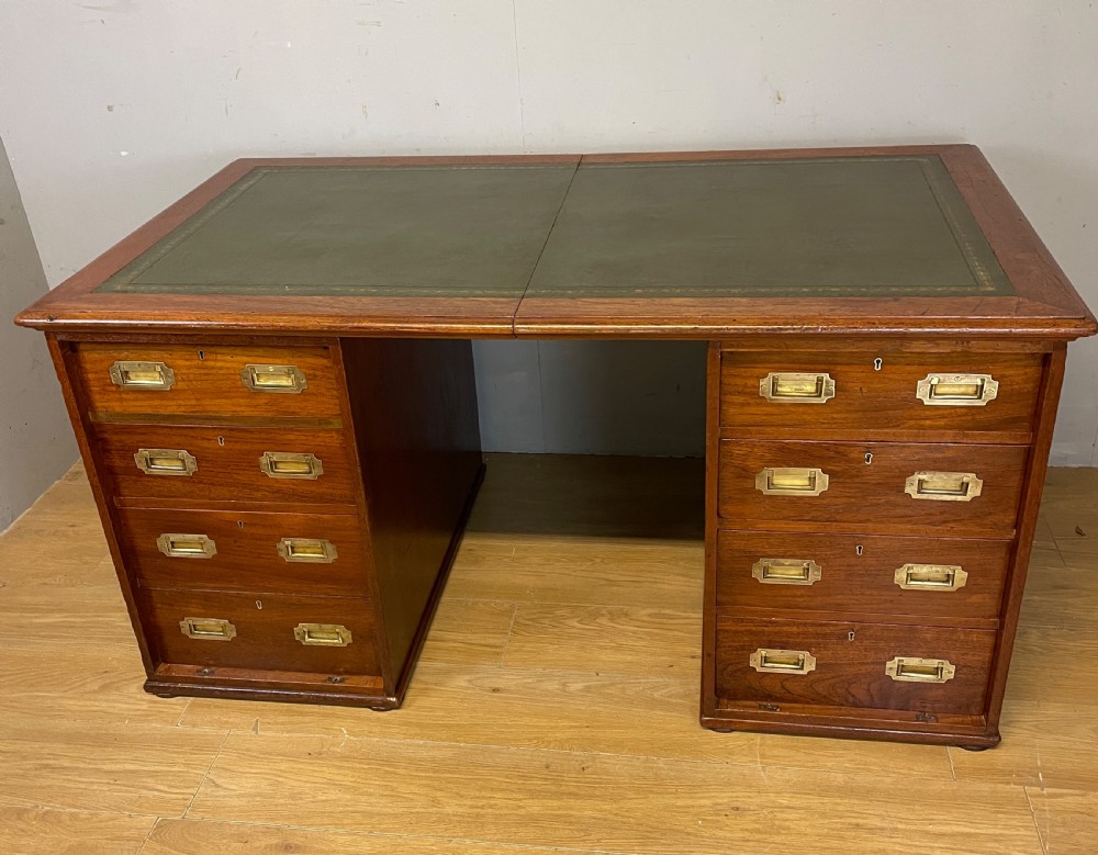 A 19th-century teak three-part military campaign desk featuring a green leather inset writing surface and flush brass drawer handles.
