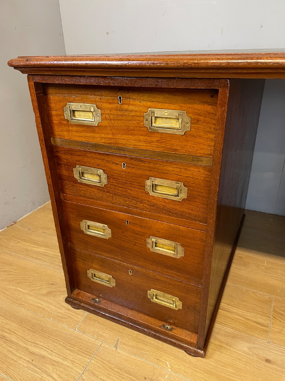 A 19th-century teak three-part military campaign desk featuring a green leather inset writing surface and flush brass drawer handles. View IV