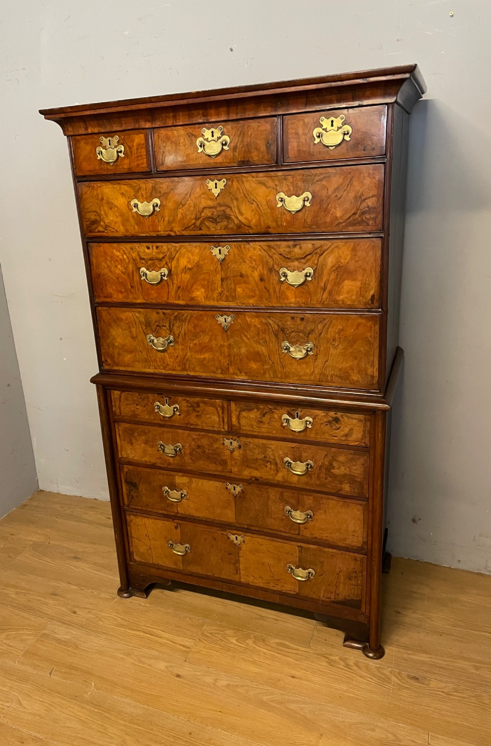 A nineteenth-century burr walnut chest on chest with multiple drawers, brass drop handles, keyhole escutcheons, and bracket feet. View II
