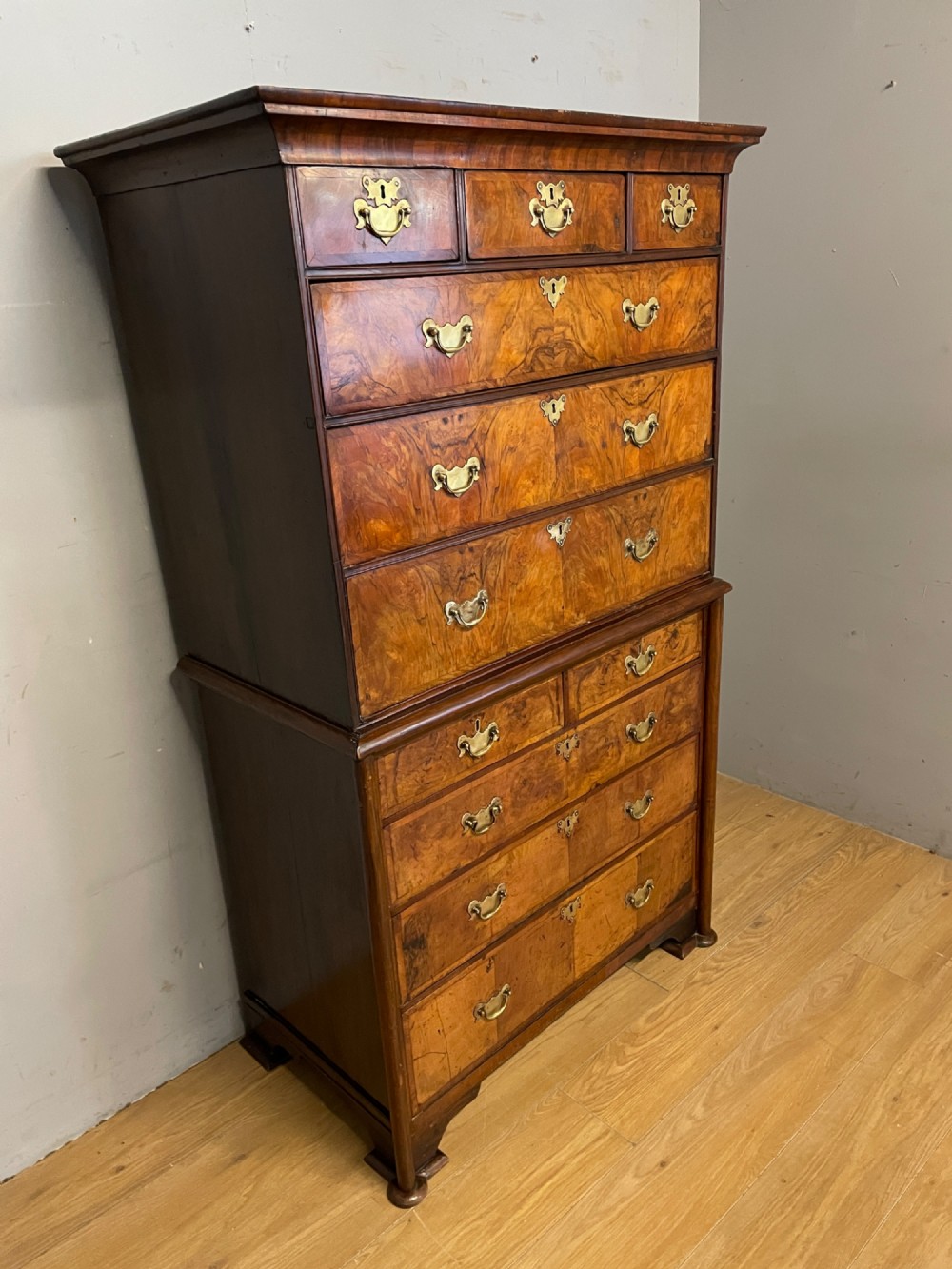A nineteenth-century burr walnut chest on chest with multiple drawers, brass drop handles, keyhole escutcheons, and bracket feet. View III