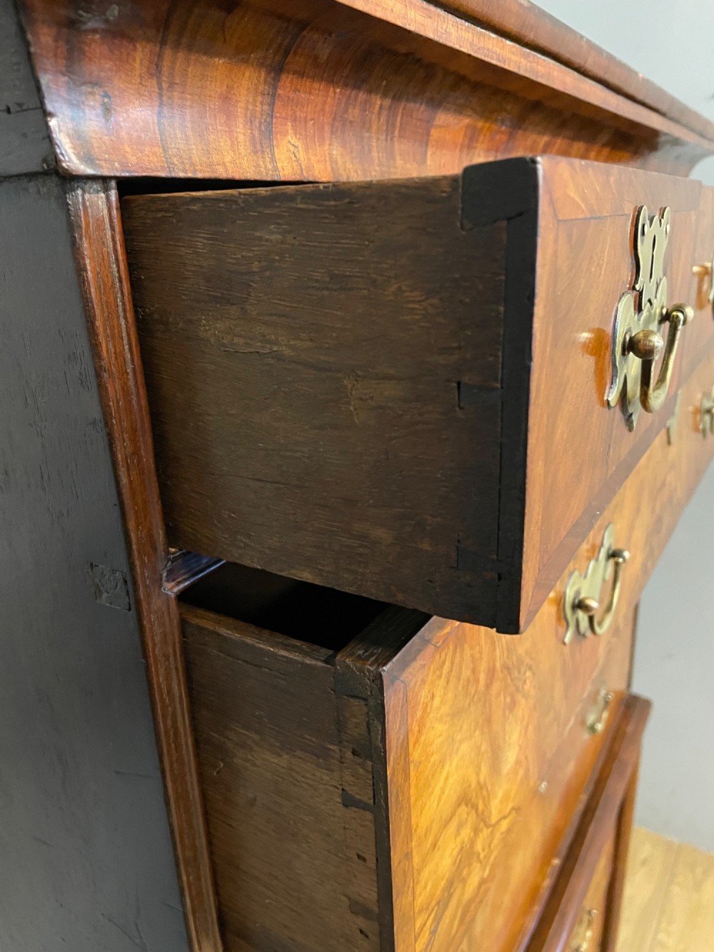 A nineteenth-century burr walnut chest on chest with multiple drawers, brass drop handles, keyhole escutcheons, and bracket feet. View VI