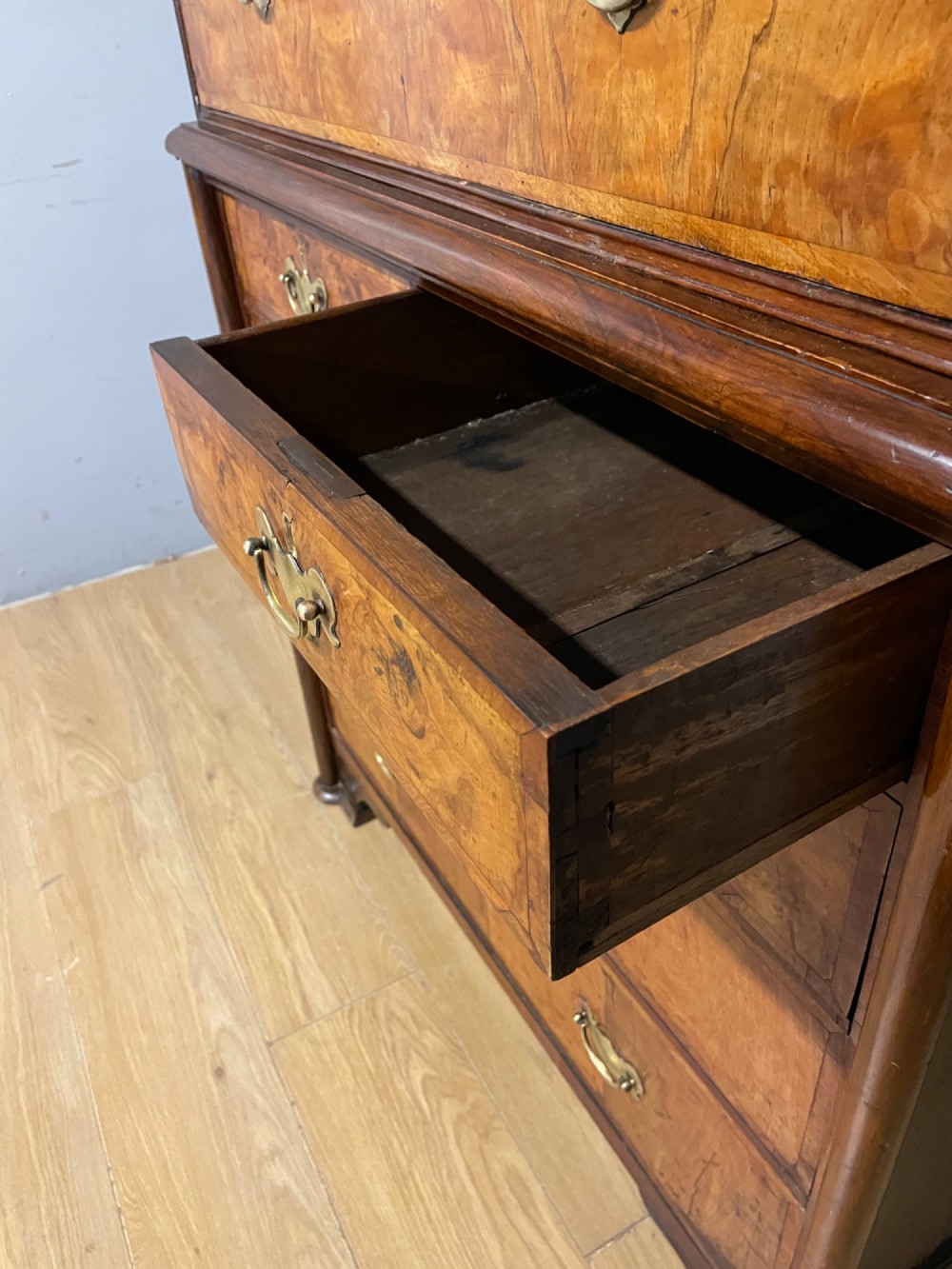 A nineteenth-century burr walnut chest on chest with multiple drawers, brass drop handles, keyhole escutcheons, and bracket feet. View VIII