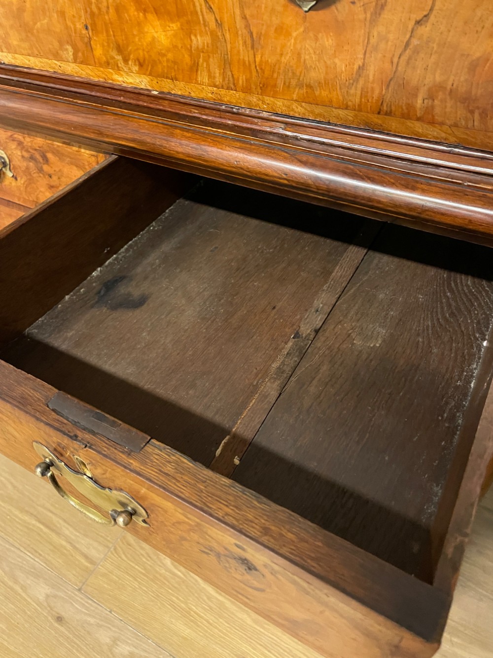 A nineteenth-century burr walnut chest on chest with multiple drawers, brass drop handles, keyhole escutcheons, and bracket feet. View IX