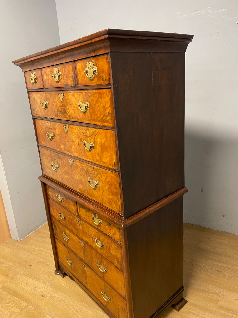 A nineteenth-century burr walnut chest on chest with multiple drawers, brass drop handles, keyhole escutcheons, and bracket feet. View XIII