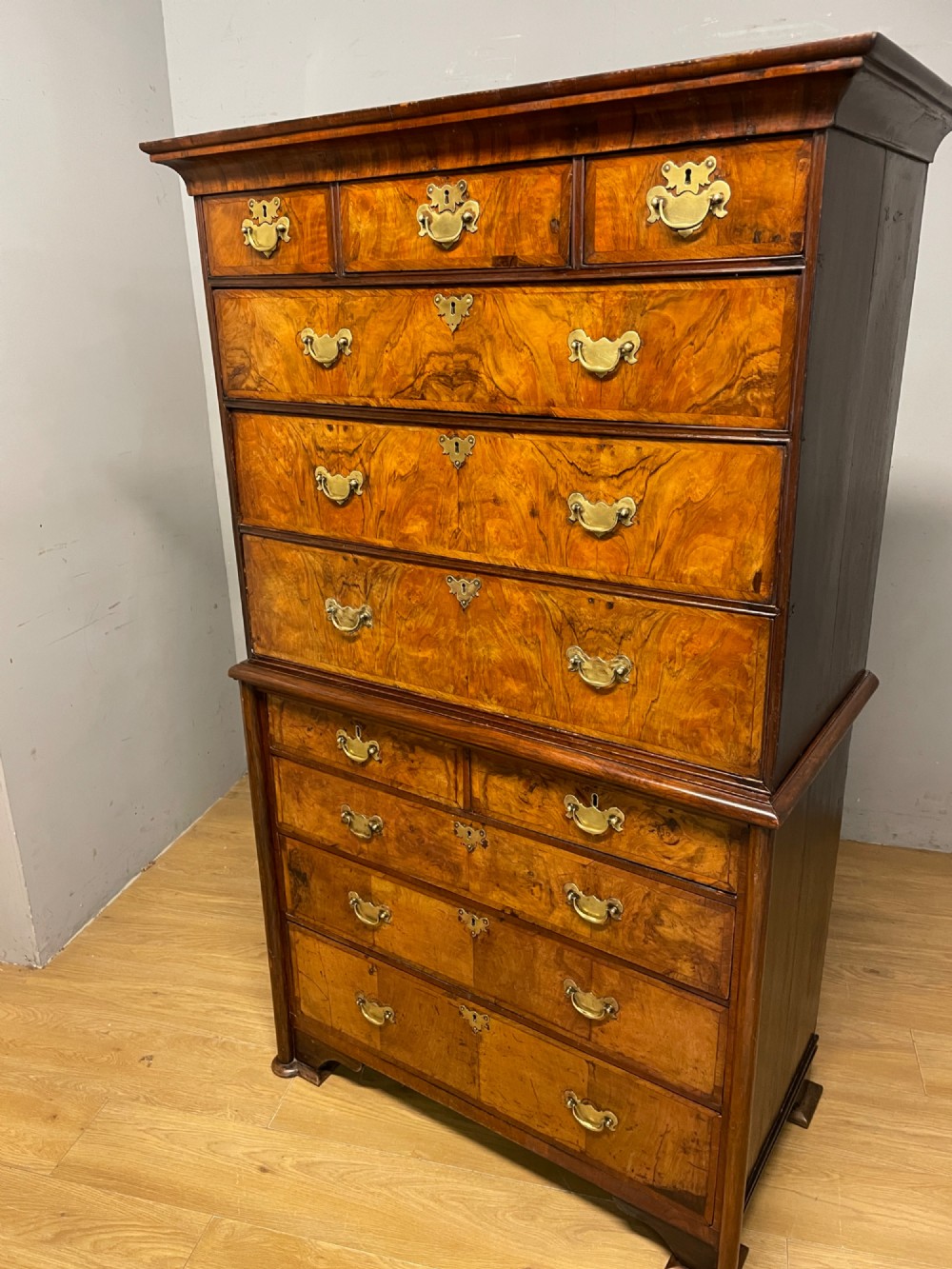 A nineteenth-century burr walnut chest on chest with multiple drawers, brass drop handles, keyhole escutcheons, and bracket feet. View XIV