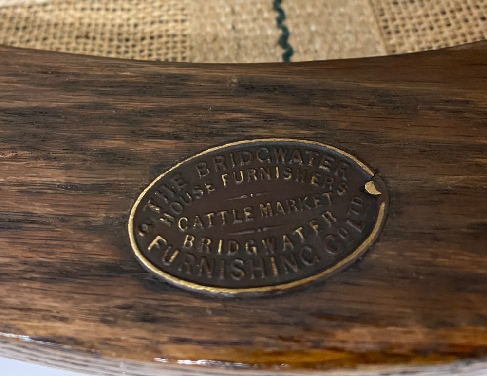 An Edwardian oak and beech desk chair featuring a curved crest rail with a cut-out handle, turned spindles, and a tan leather seat secured with brass studs. View VIII