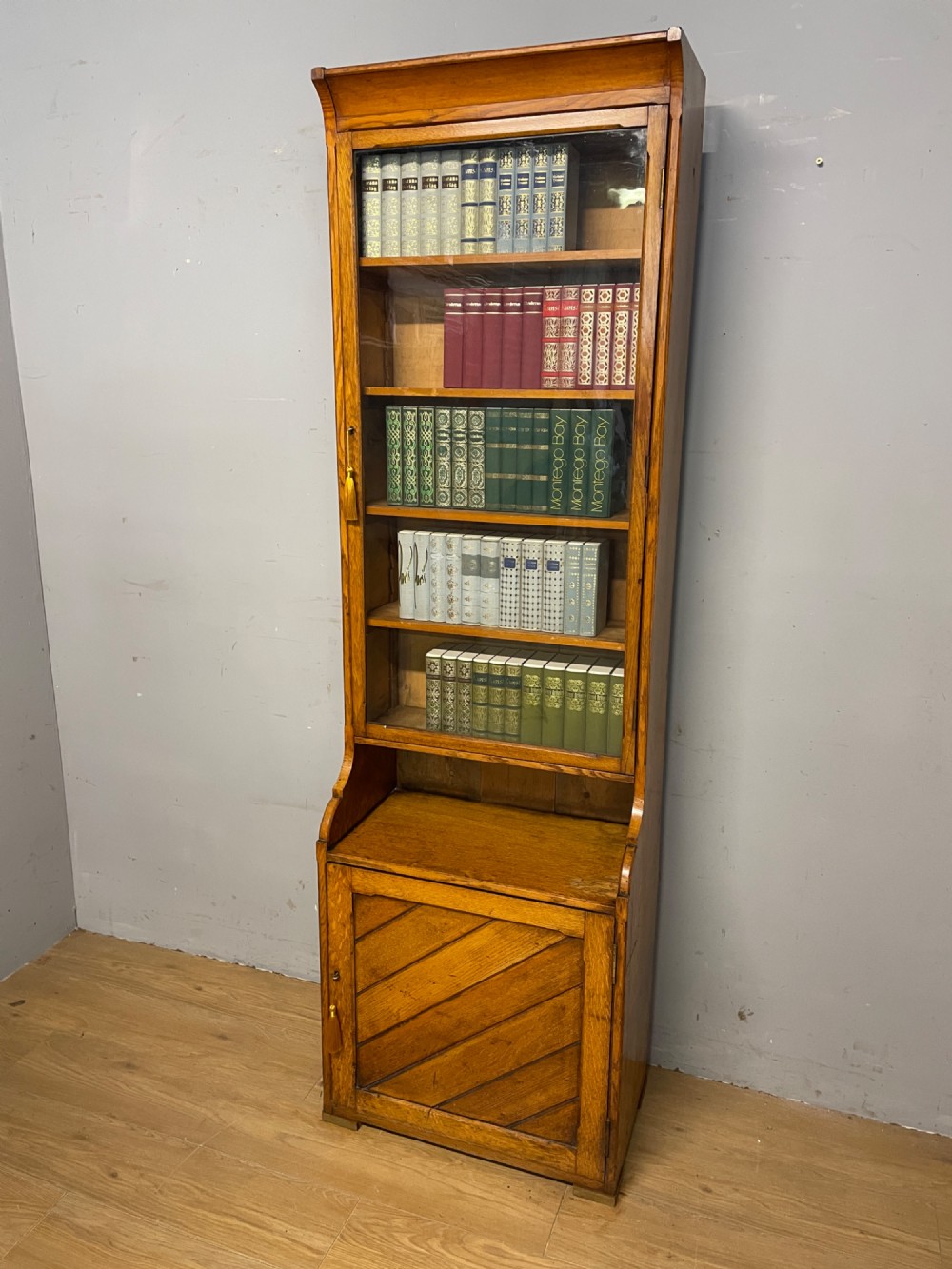 Arts and Crafts golden oak slim bookcase over cupboard