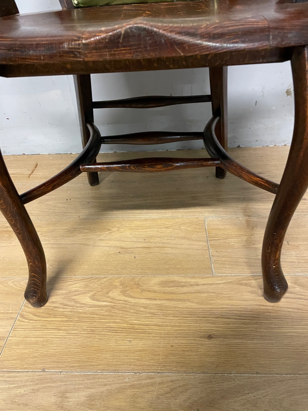 Late nineteenth-century solid oak desk chair featuring sweeping arms, a contoured timber seat, and an olive green leather back panel secured with brass studding. View IX