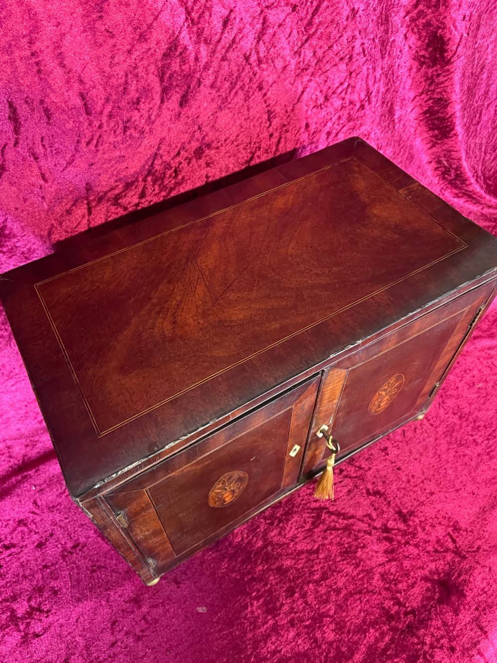 A Georgian dark mahogany tabletop cabinet featuring double doors with oval marquetry urn inlays, diamond escutcheons, and brass ball feet. View V