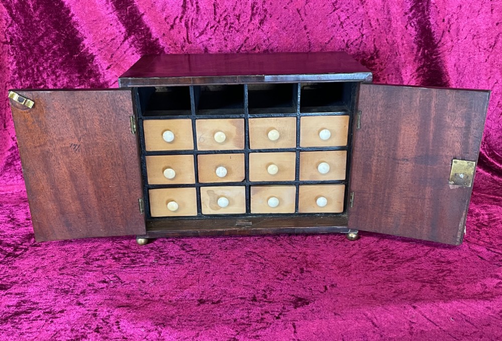 A Georgian dark mahogany tabletop cabinet featuring double doors with oval marquetry urn inlays, diamond escutcheons, and brass ball feet. View VI