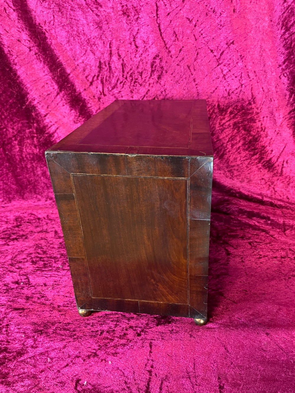 A Georgian dark mahogany tabletop cabinet featuring double doors with oval marquetry urn inlays, diamond escutcheons, and brass ball feet. View VIII