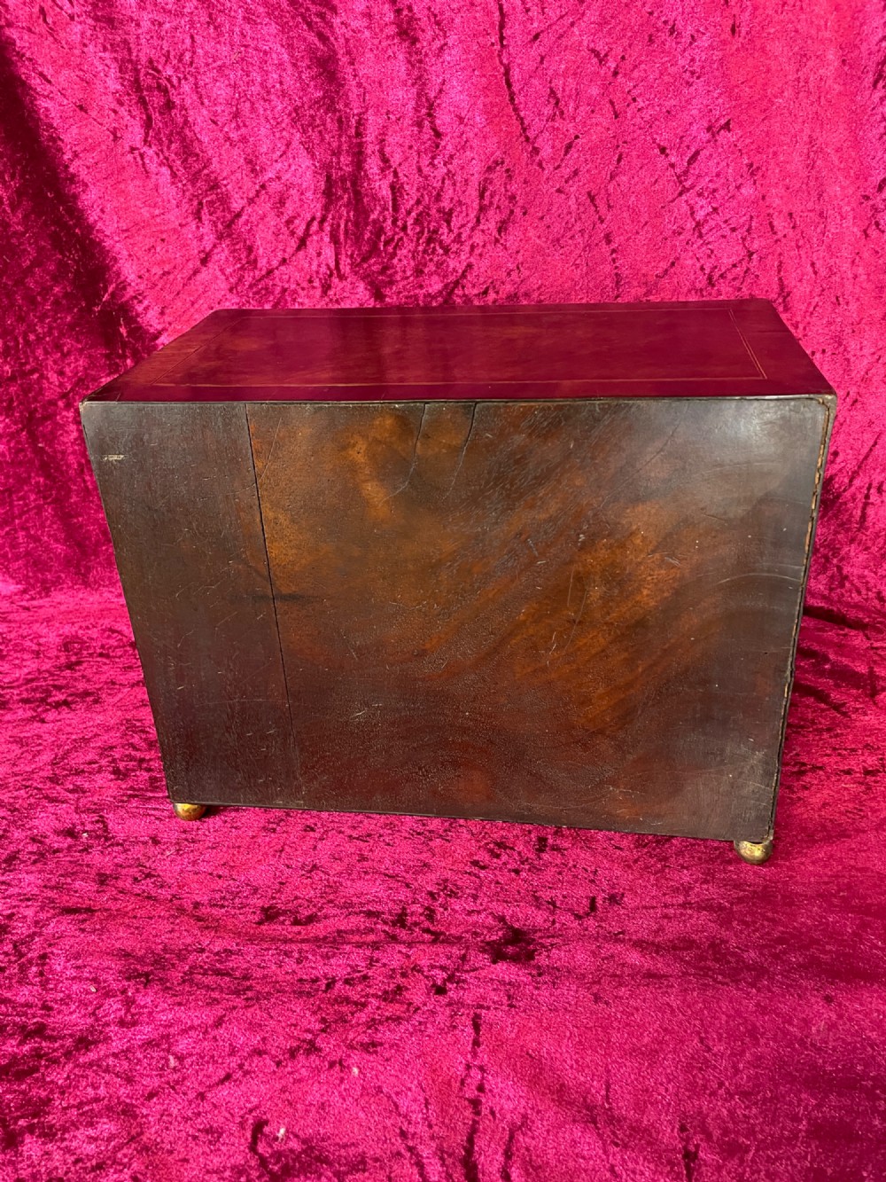A Georgian dark mahogany tabletop cabinet featuring double doors with oval marquetry urn inlays, diamond escutcheons, and brass ball feet. View IX