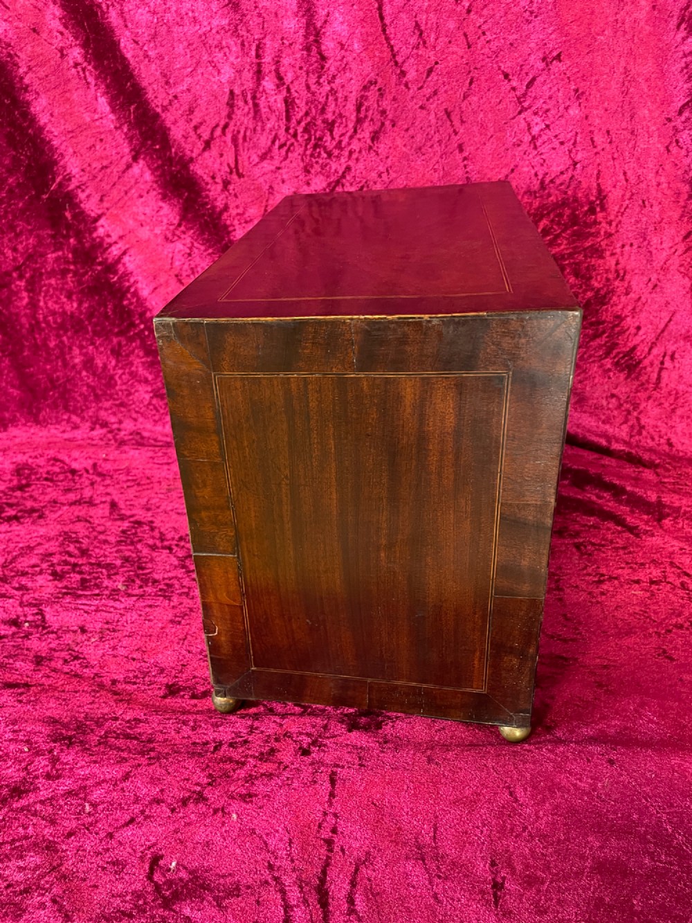 A Georgian dark mahogany tabletop cabinet featuring double doors with oval marquetry urn inlays, diamond escutcheons, and brass ball feet. View X