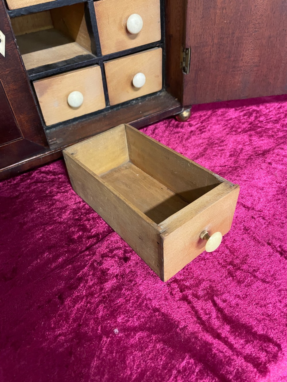 A Georgian dark mahogany tabletop cabinet featuring double doors with oval marquetry urn inlays, diamond escutcheons, and brass ball feet. View XIII