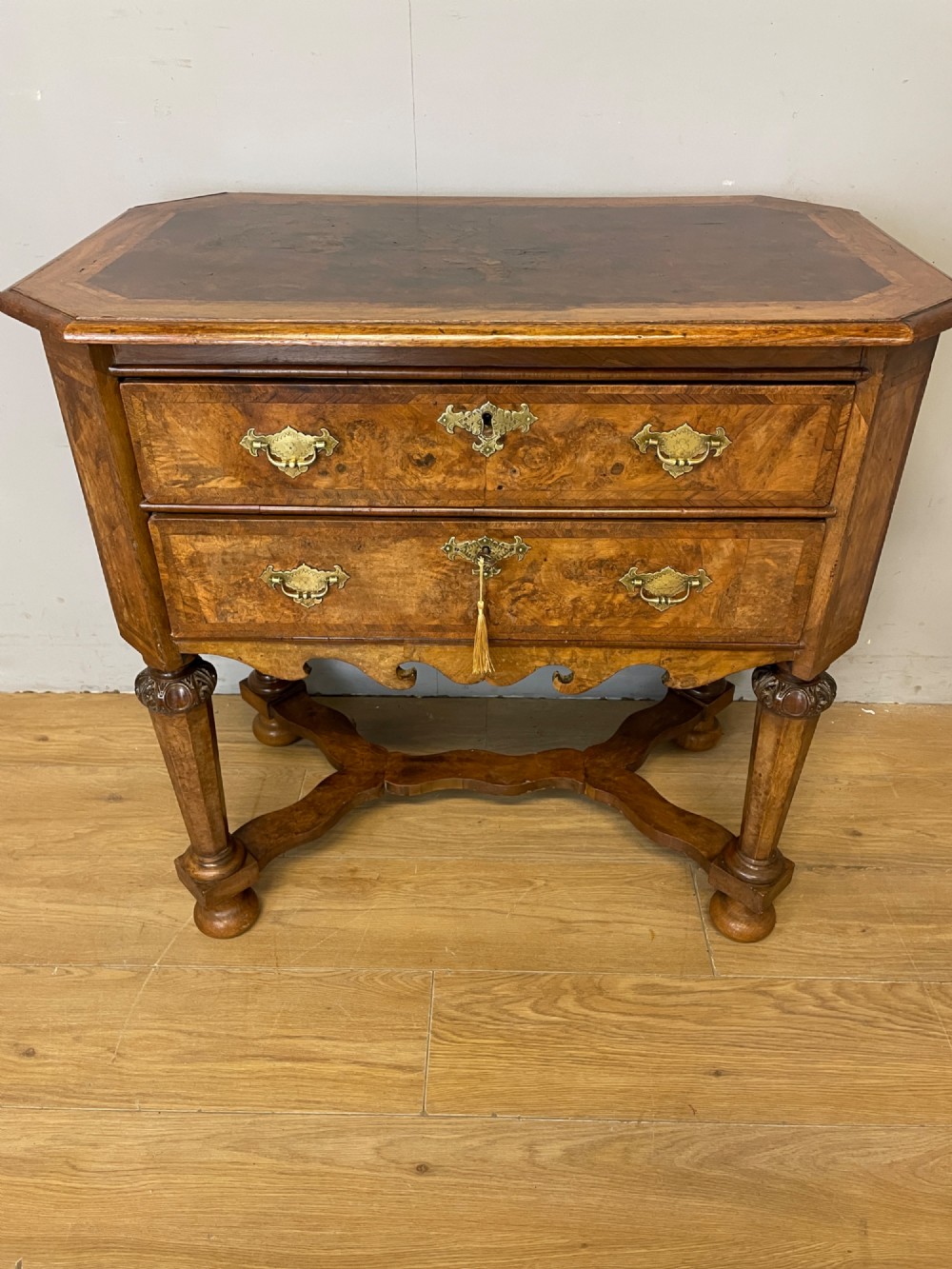 A late Victorian burr walnut lowboy featuring two drawers with brass handles, carved legs, and a shaped cross-stretcher. View II