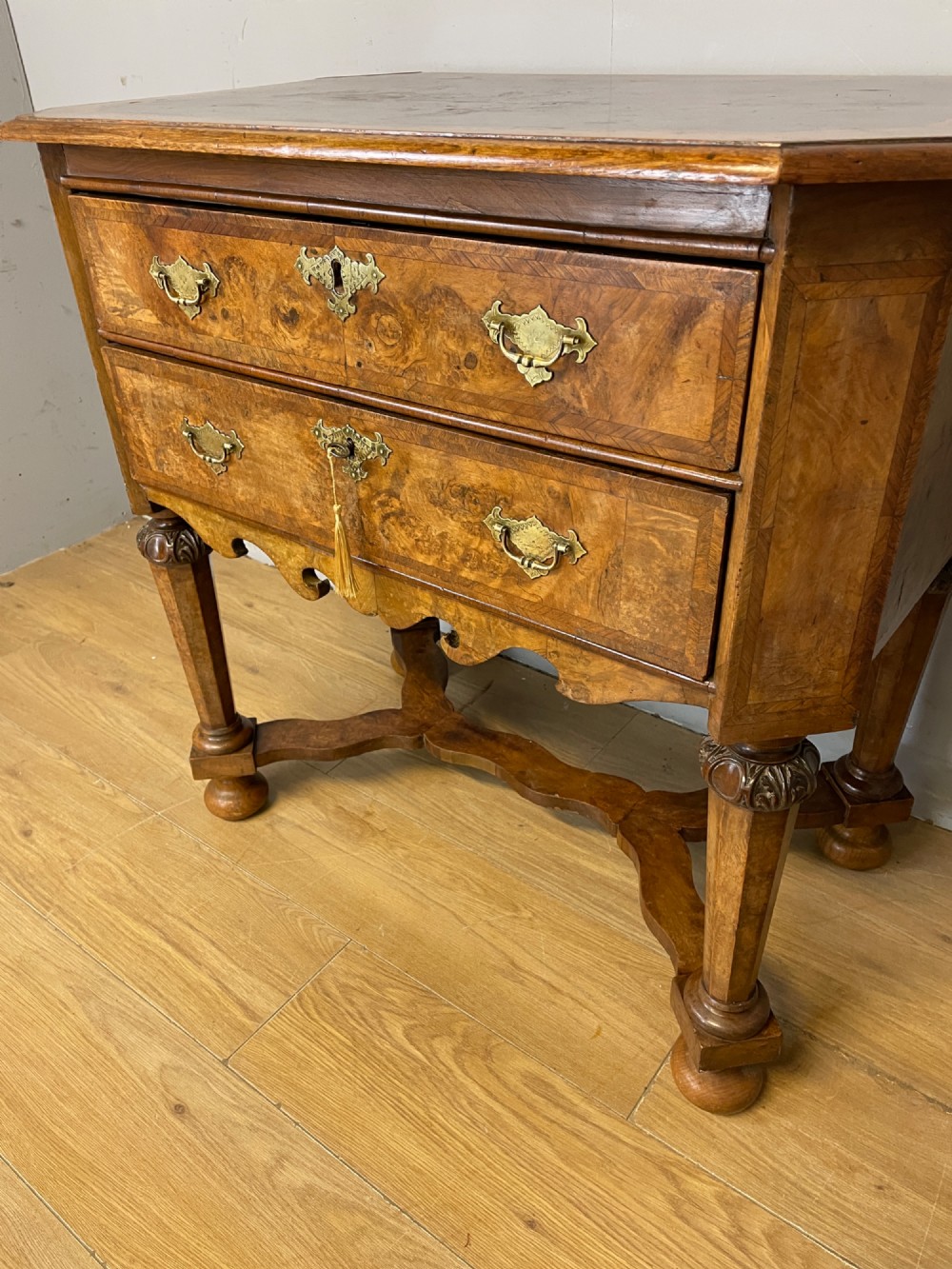 A late Victorian burr walnut lowboy featuring two drawers with brass handles, carved legs, and a shaped cross-stretcher. View IV