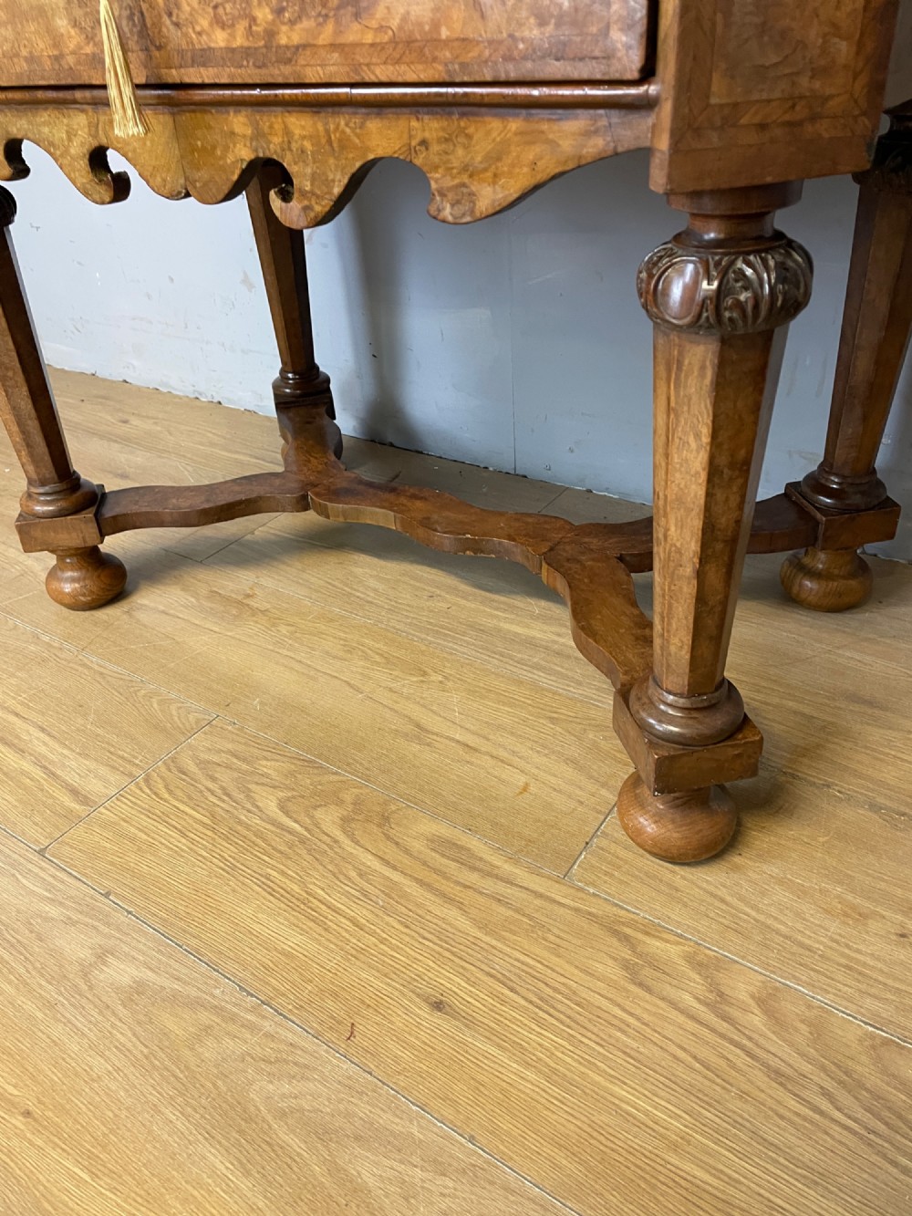 A late Victorian burr walnut lowboy featuring two drawers with brass handles, carved legs, and a shaped cross-stretcher. View V