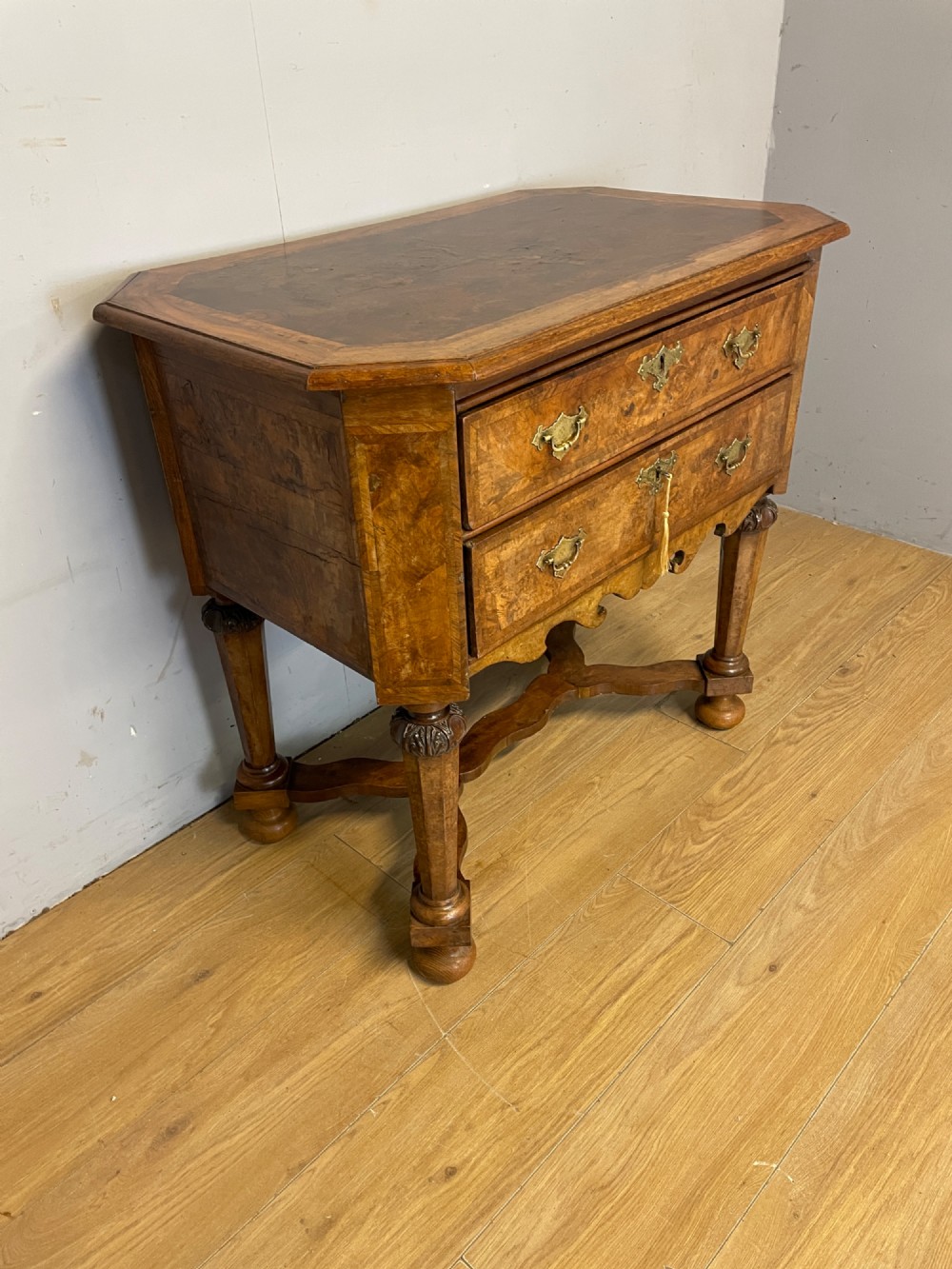 A late Victorian burr walnut lowboy featuring two drawers with brass handles, carved legs, and a shaped cross-stretcher. View VI