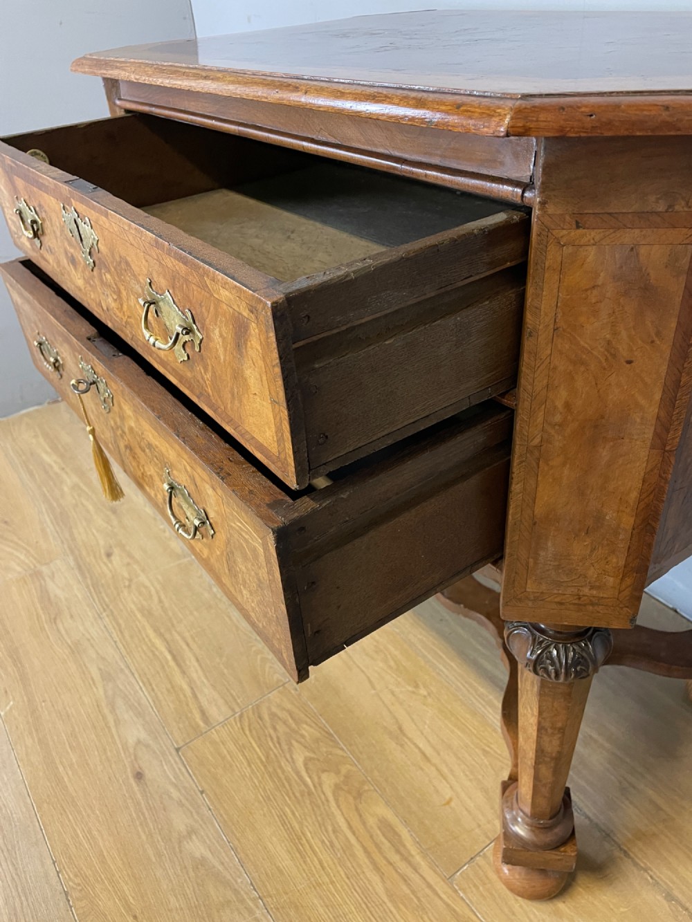 A late Victorian burr walnut lowboy featuring two drawers with brass handles, carved legs, and a shaped cross-stretcher. View IX