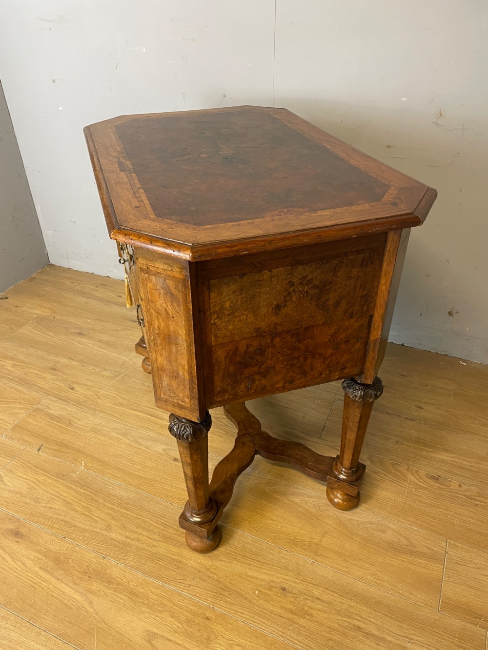 A late Victorian burr walnut lowboy featuring two drawers with brass handles, carved legs, and a shaped cross-stretcher. View X