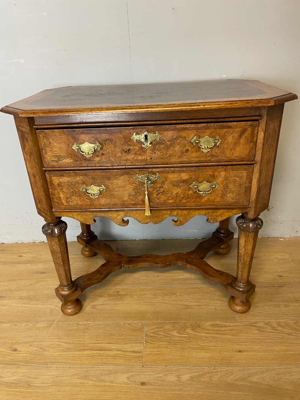 A late Victorian burr walnut lowboy featuring two drawers with brass handles, carved legs, and a shaped cross-stretcher. View XIV