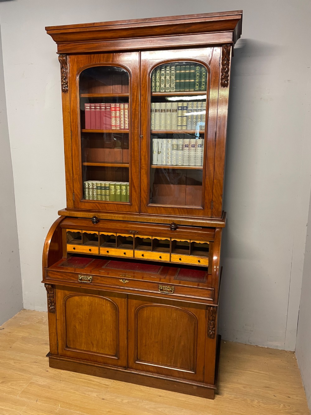 A 19th-century mahogany cylinder bureau bookcase featuring an upper glazed cabinet with two arched doors, a roll-top writing section, and a lower two-door cupboard. View III
