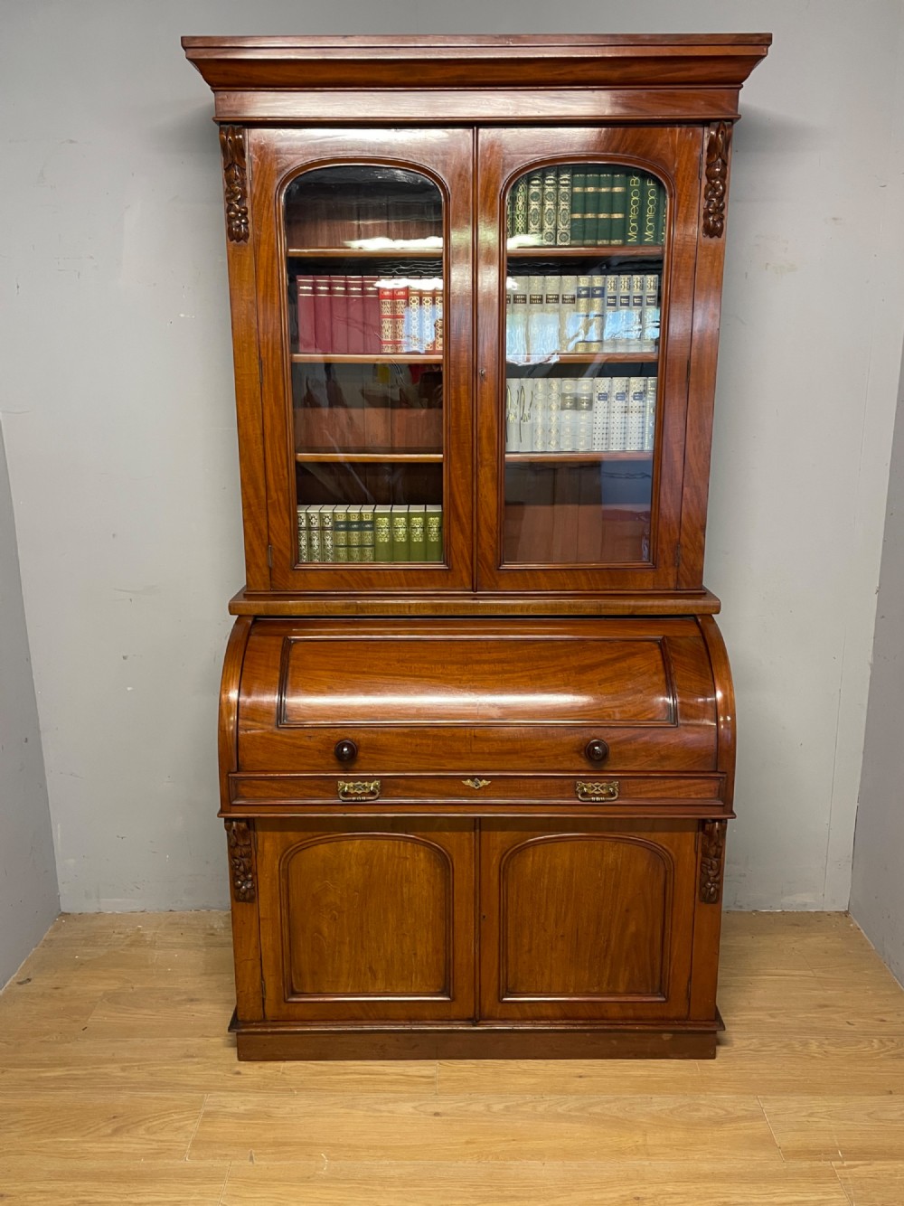 A 19th-century mahogany cylinder bureau bookcase featuring an upper glazed cabinet with two arched doors, a roll-top writing section, and a lower two-door cupboard. View IV