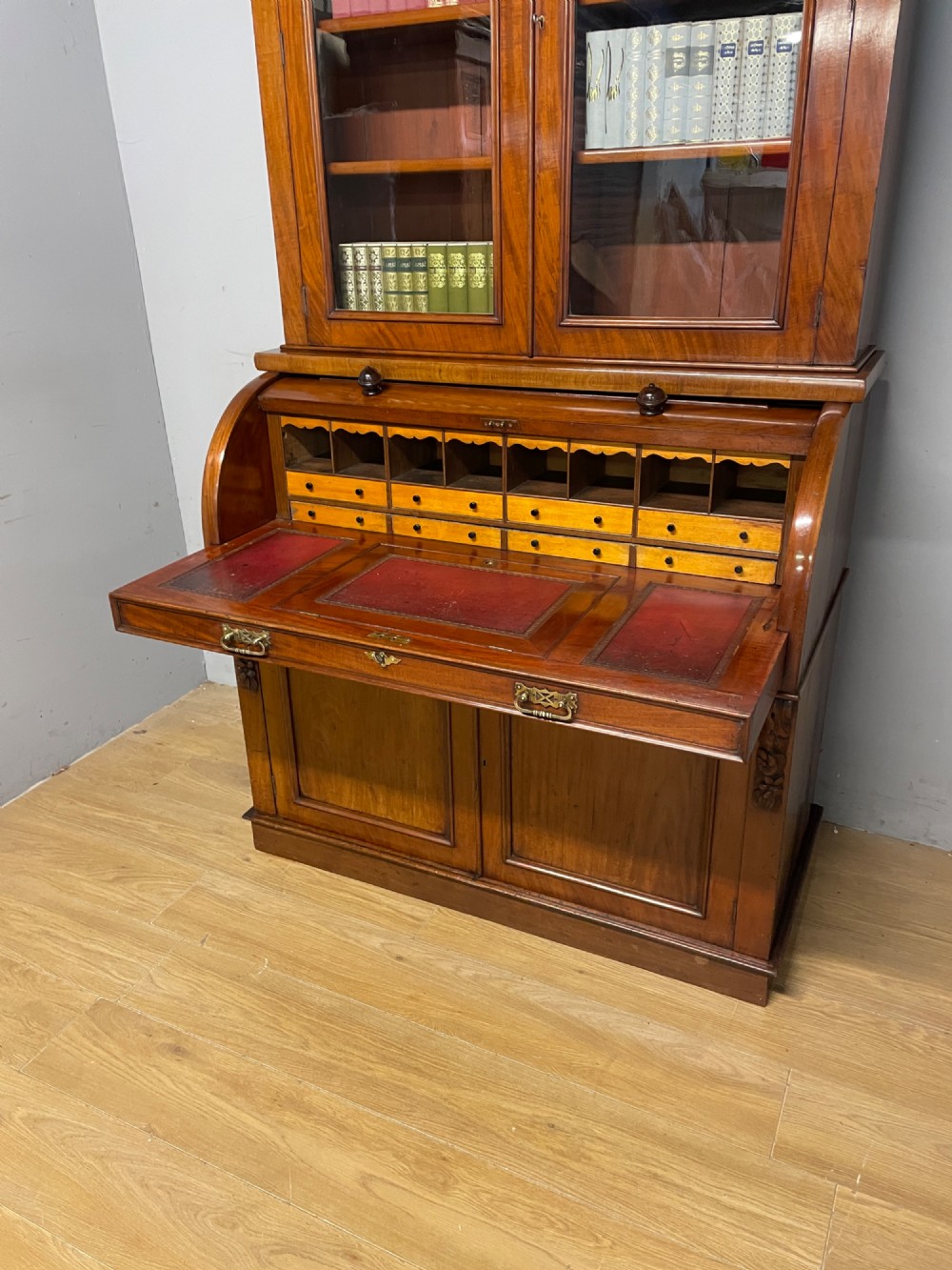 A 19th-century mahogany cylinder bureau bookcase featuring an upper glazed cabinet with two arched doors, a roll-top writing section, and a lower two-door cupboard. View VI