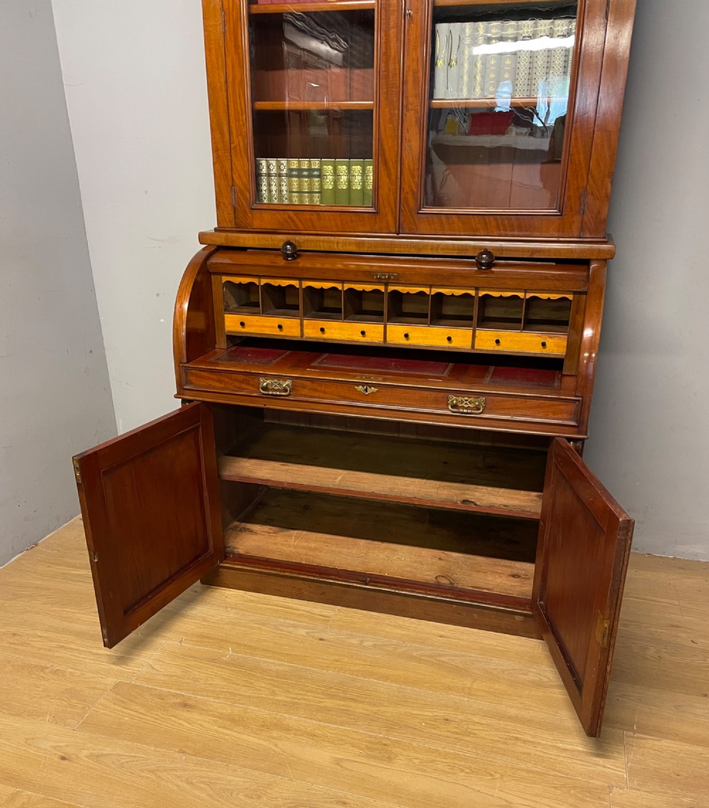 A 19th-century mahogany cylinder bureau bookcase featuring an upper glazed cabinet with two arched doors, a roll-top writing section, and a lower two-door cupboard. View XI