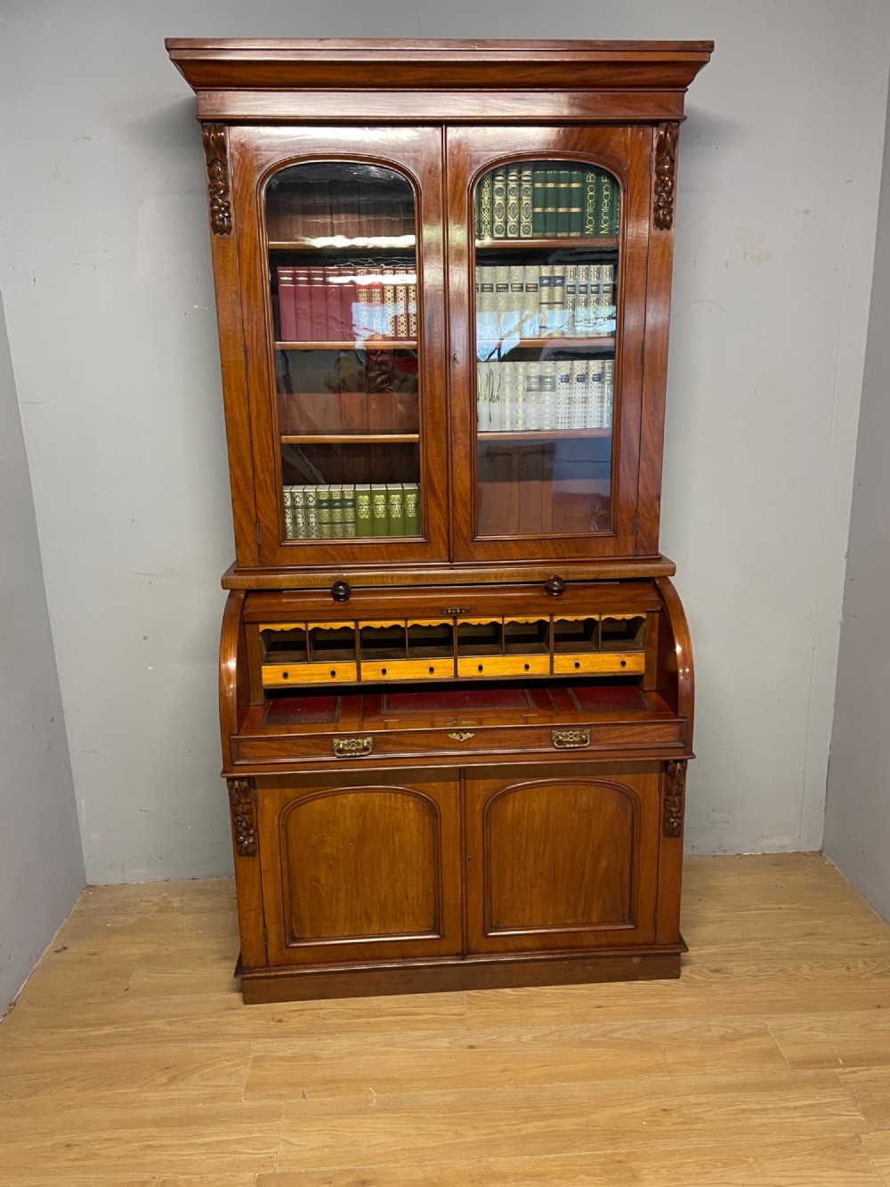 A 19th-century mahogany cylinder bureau bookcase featuring an upper glazed cabinet with two arched doors, a roll-top writing section, and a lower two-door cupboard. View XIV