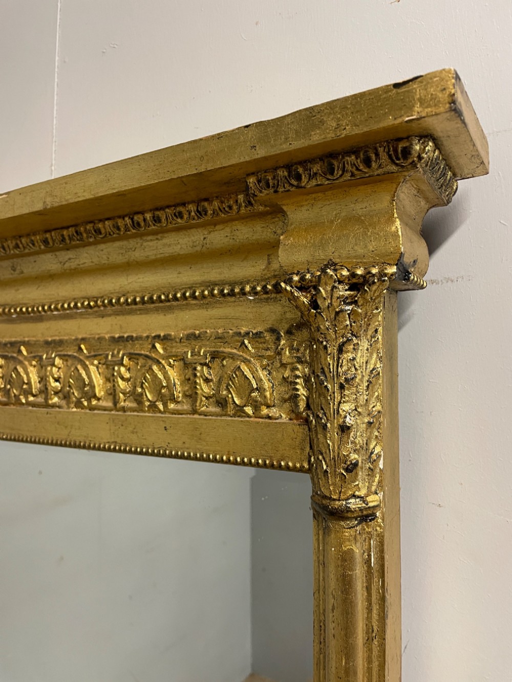 A rectangular giltwood wall mirror featuring a projecting cornice top, classical column pilasters, arcaded frieze details, and rosette corner blocks. View III