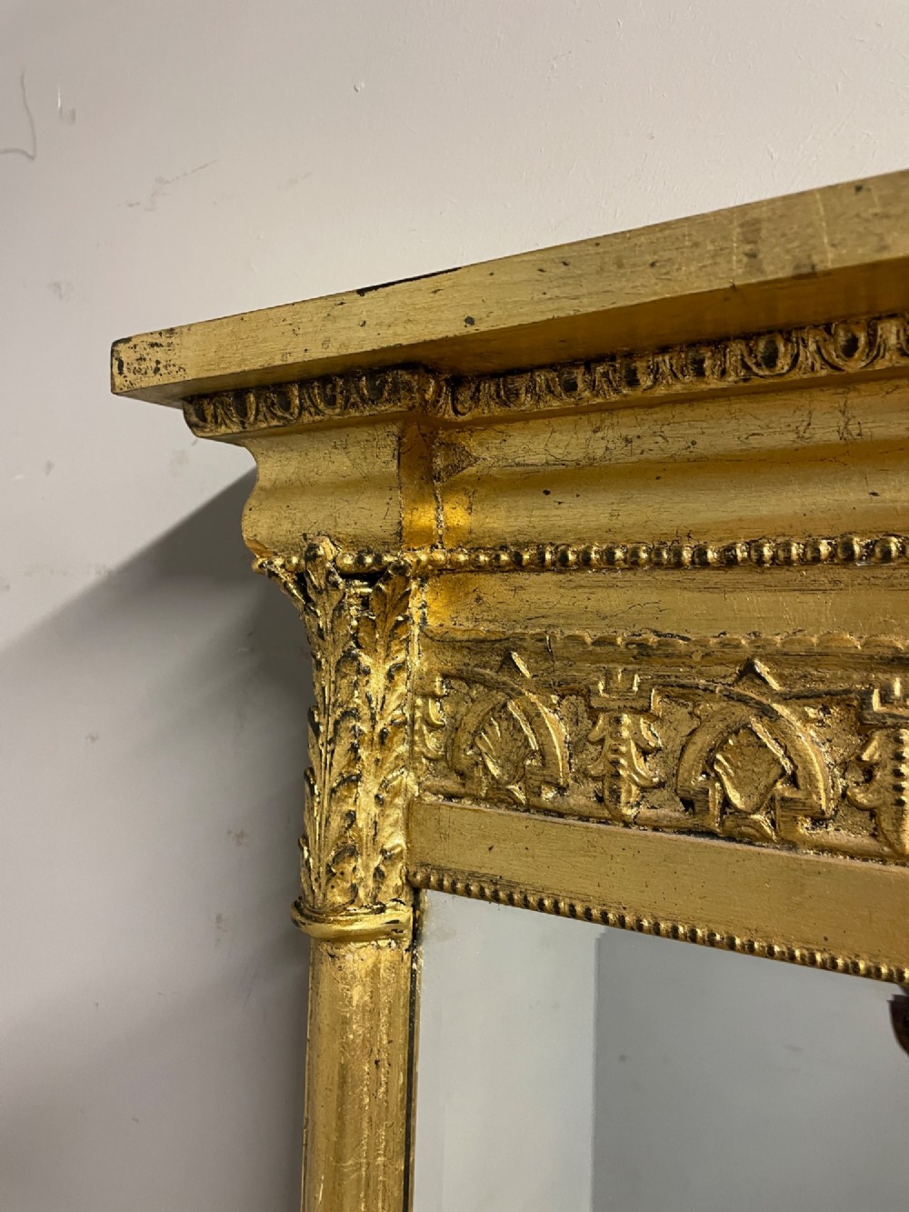 A rectangular giltwood wall mirror featuring a projecting cornice top, classical column pilasters, arcaded frieze details, and rosette corner blocks. View V