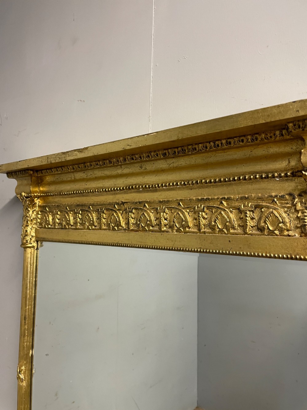 A rectangular giltwood wall mirror featuring a projecting cornice top, classical column pilasters, arcaded frieze details, and rosette corner blocks. View VI