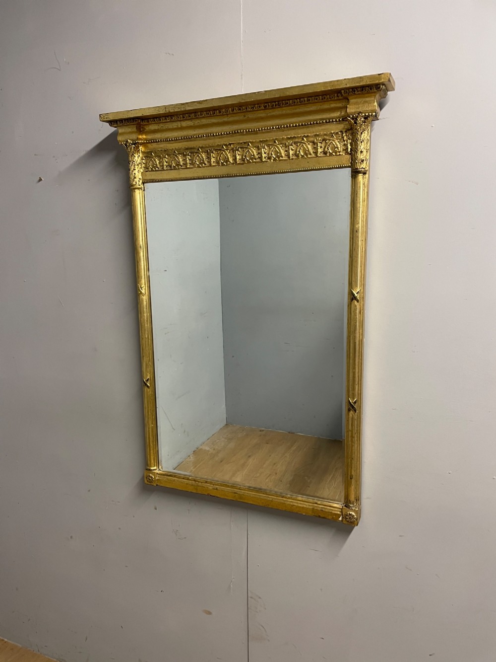 A rectangular giltwood wall mirror featuring a projecting cornice top, classical column pilasters, arcaded frieze details, and rosette corner blocks. View VIII