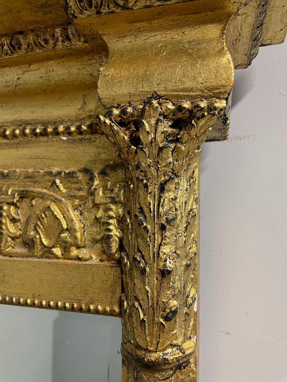 A rectangular giltwood wall mirror featuring a projecting cornice top, classical column pilasters, arcaded frieze details, and rosette corner blocks. View IX