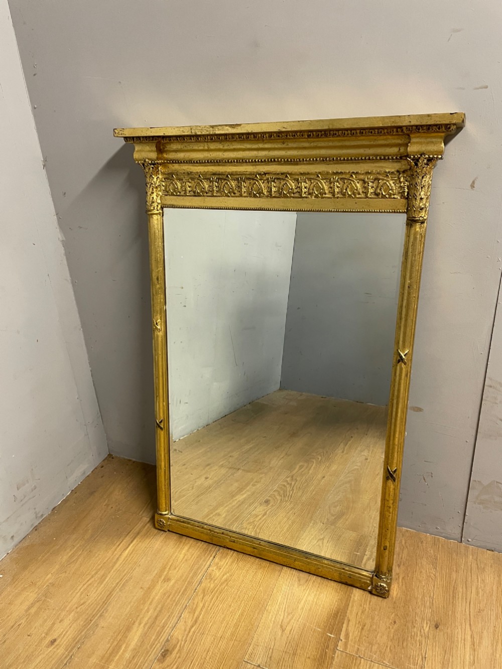 A rectangular giltwood wall mirror featuring a projecting cornice top, classical column pilasters, arcaded frieze details, and rosette corner blocks. View X