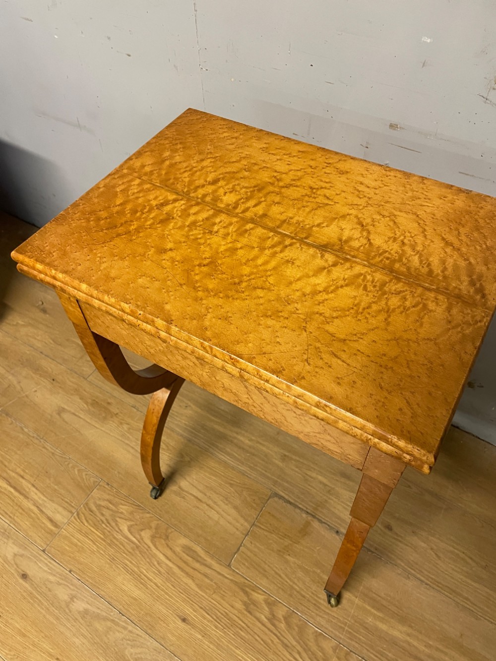 A 19th-century Biedermeier birds eye maple card table featuring a rectangular fold-over top, sweeping legs, a turned central stretcher, and brass castors. View VIII