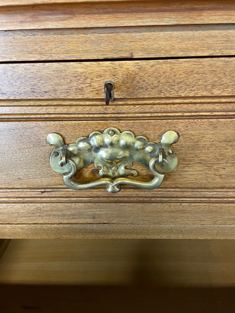 An Arts and Crafts satin walnut chest of drawers featuring two short over three long drawers with brass drop handles and a solid plinth base. View VII