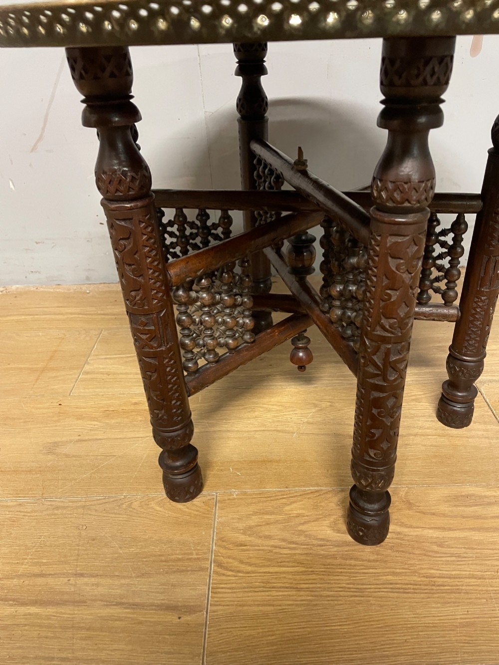 A late 19th-century Anglo-Indian Benares table featuring an intricately engraved circular brass tray top resting on a dark carved wooden folding base. View III