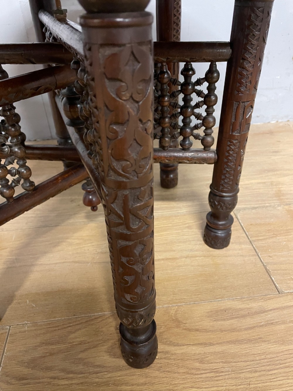 A late 19th-century Anglo-Indian Benares table featuring an intricately engraved circular brass tray top resting on a dark carved wooden folding base. View VI