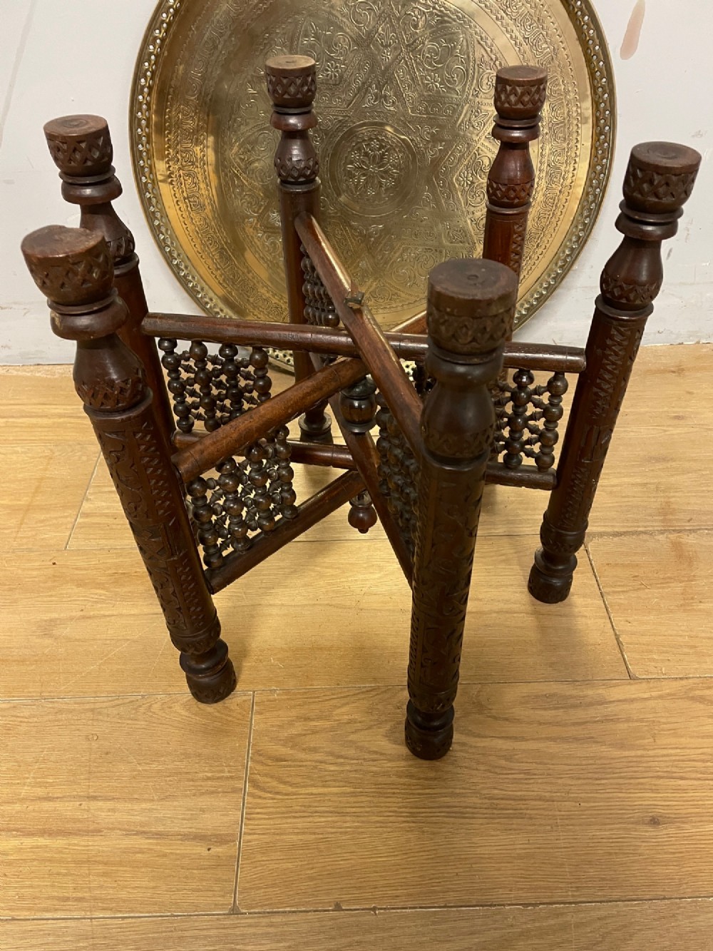 A late 19th-century Anglo-Indian Benares table featuring an intricately engraved circular brass tray top resting on a dark carved wooden folding base. View VII