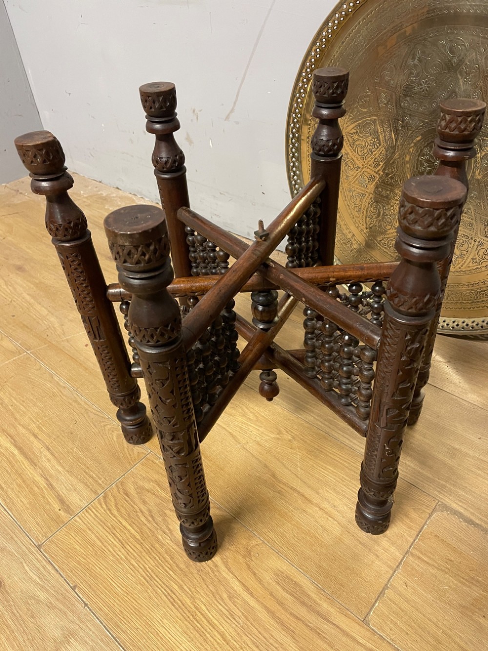 A late 19th-century Anglo-Indian Benares table featuring an intricately engraved circular brass tray top resting on a dark carved wooden folding base. View VIII