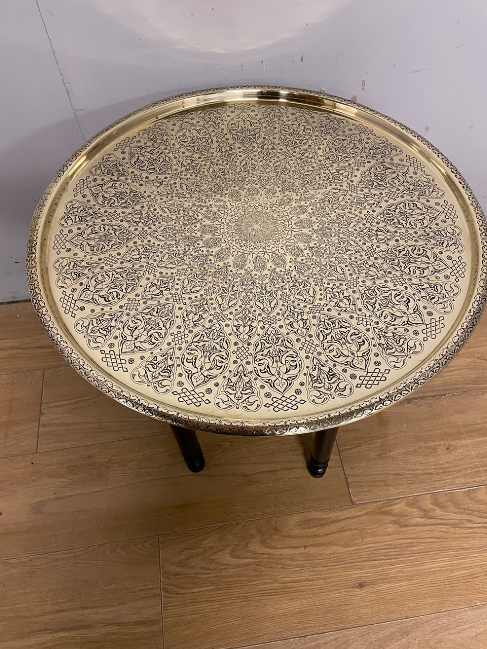 An Anglo-Indian circular brass tray table with hand-engraved patterns supported on an ebonised wooden base with turned legs. View III