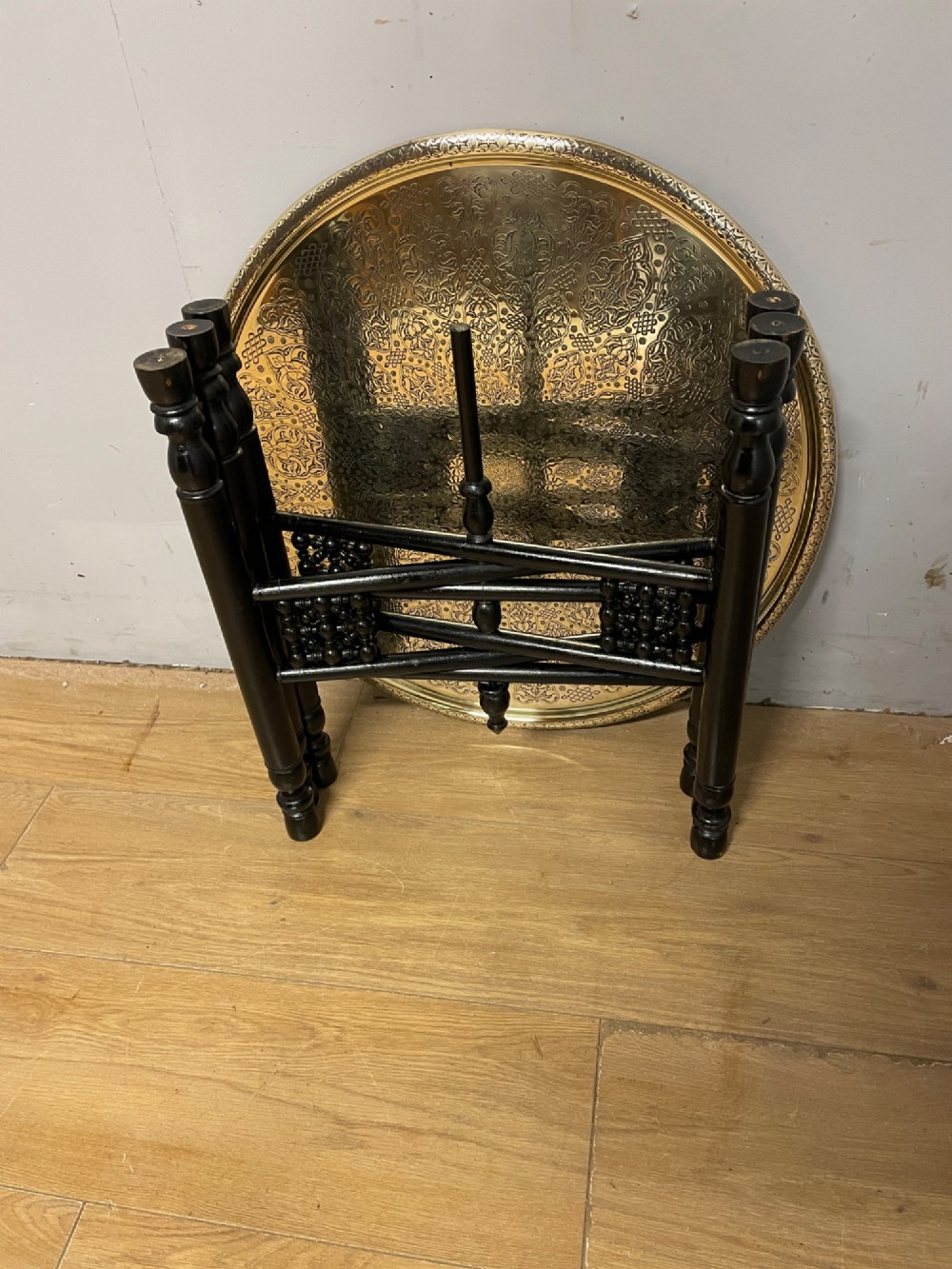 An Anglo-Indian circular brass tray table with hand-engraved patterns supported on an ebonised wooden base with turned legs. View VIII