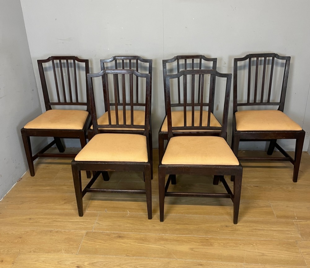 A set of six late Georgian dark mahogany country-made dining chairs featuring vertical bar backs and padded light tan upholstered drop-in seats. View II